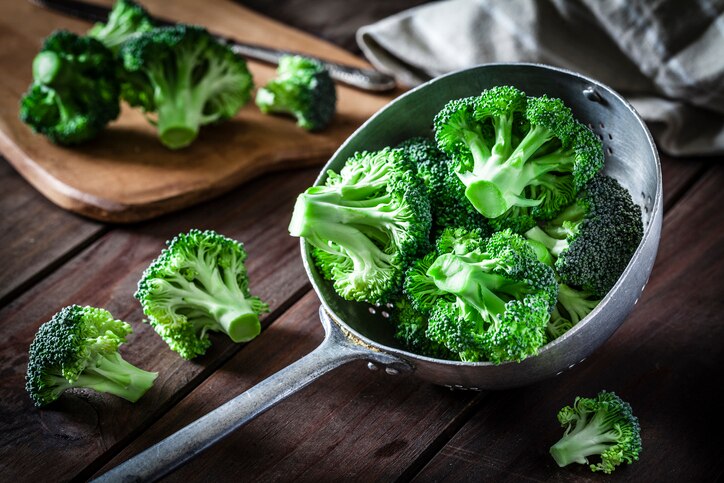 Fresh organic broccoli in an old metal colander shot on rustic wooden table. This vegetable is considered a healthy salad ingredient. Predominant colors are green and brown. Low key DSRL studio photo taken with Canon EOS 5D Mk II and Canon EF 100mm f/2.8L Macro IS USM