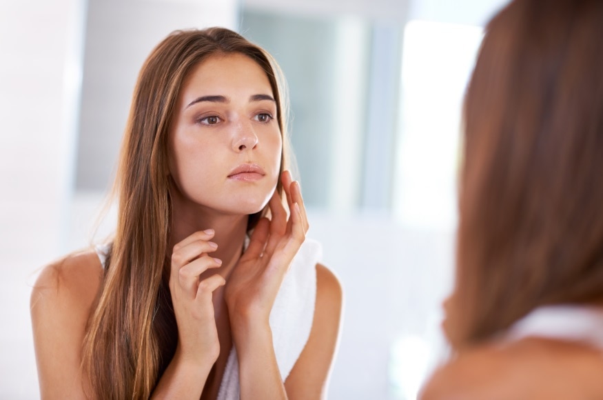 Over the shoulder shot of an attractive young woman looking at her reflection in a mirror