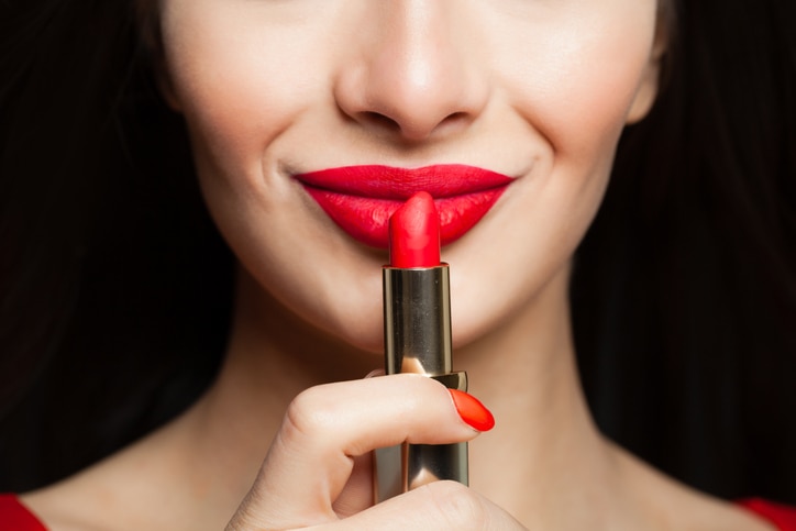 Female face closeup. Red lips makeup with bright red lipstick on black background