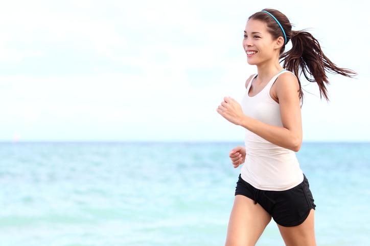 Running woman. Female runner jogging during outdoor workout on beach. Beautiful fit mixed race Fitness model outdoors.