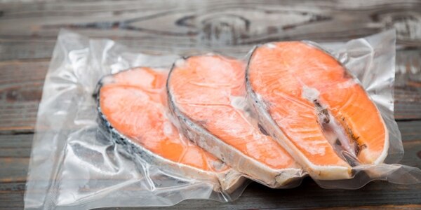 Frozen salmon fillets in a vacuum package wood table