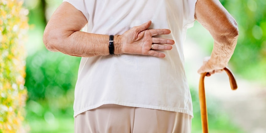 Elderly woman outdoors with lower back pain