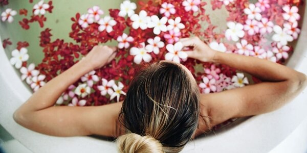 53055879 - woman relaxing in round outdoor bath with tropical flowers, organic skin care, luxury spa hotel, lifestyle photo, top view